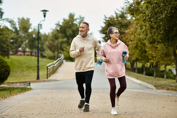 Pareja corre alegremente en un hermoso parque, rodeado de exuberante vegetación. - foto de stock