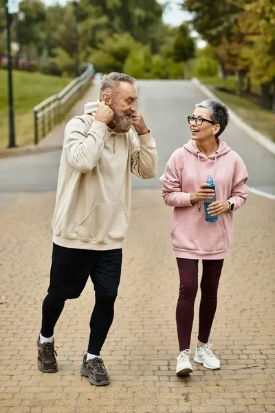 Mature couple shares laughter and love during a relaxing walk in a beautiful park setting. — Stock Photo