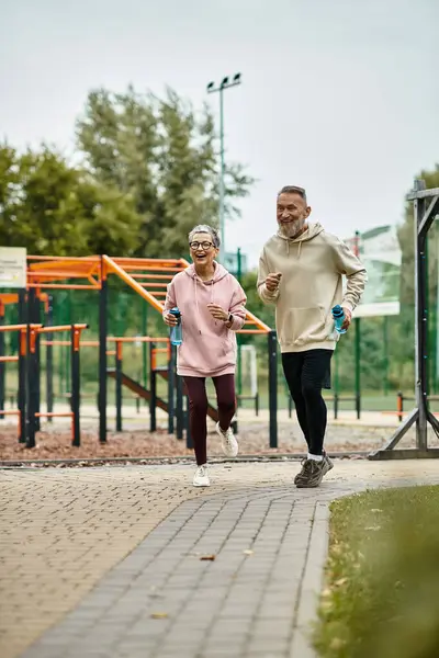 A loving couple enjoys jogging in a serene park, embracing fitness and connection in nature. — Stock Photo