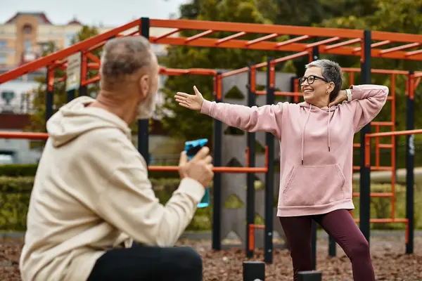A loving couple enjoys playful interactions while exercising together in a lively park. — Stock Photo
