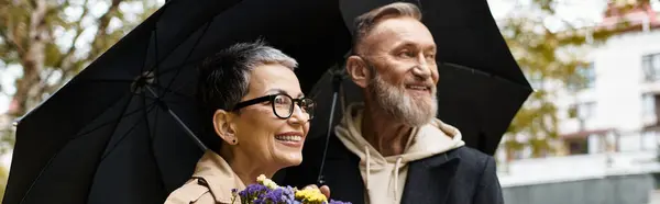 A happy couple enjoys their time together while shielding from rain, surrounded by natures beauty. — Stock Photo