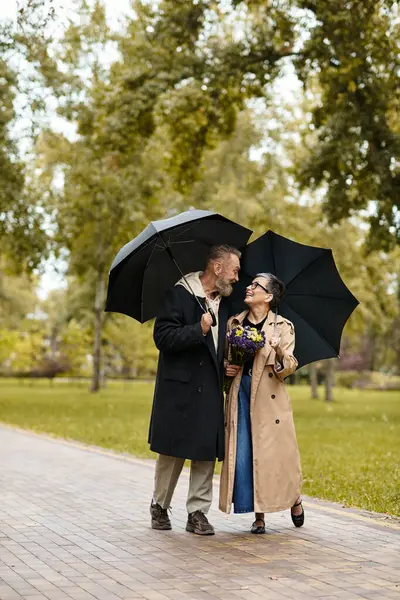 A loving couple strolls together under matching umbrellas, exchanging smiles and affection. — Stock Photo