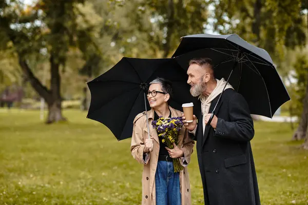 A loving couple shares laughter while walking together in a vibrant park, enjoying nature. — Stock Photo