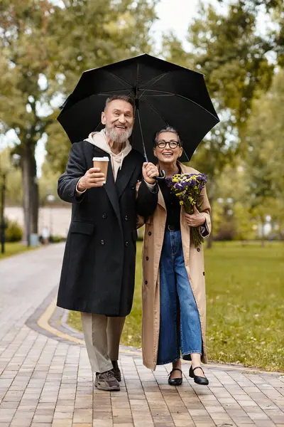 A loving couple strolls through a park, sharing smiles and warm moments with flowers and coffee. — Stock Photo