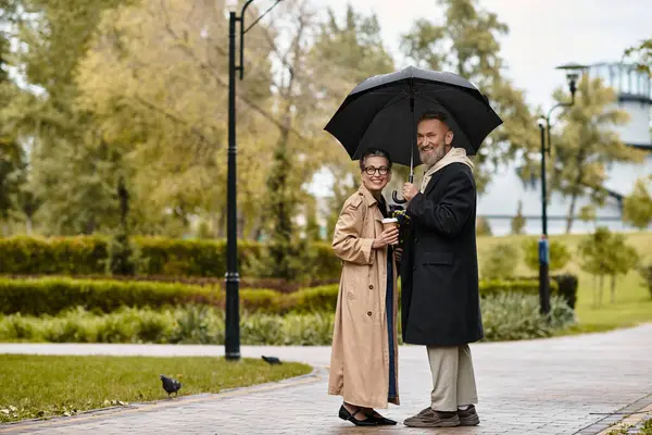 A loving couple shares a warm, peaceful walk together away from the rain. — Stock Photo