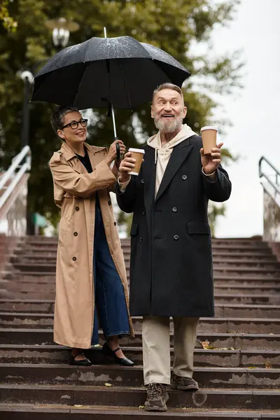 A happy couple enjoys a rainy day together, sharing laughter while sipping on warm drinks. — Stock Photo