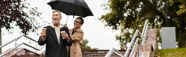 A couple shares laughter in the rain, enjoying each others warmth and company. — Stock Photo