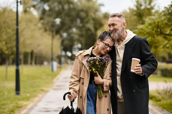 A mature couple enjoys a heartfelt moment while strolling through a lush park, surrounded by nature. — Stock Photo