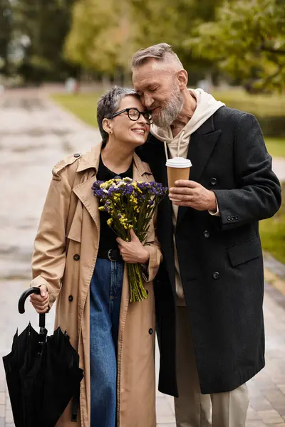In a lovely park setting, a mature couple enjoys each others company while sharing a warm embrace. — Stock Photo