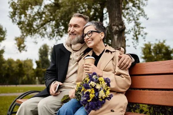 Ein reifes Paar genießt den gemeinsamen Kaffee, teilt Blumen und strahlt Liebe und Glück aus. — Stockfoto