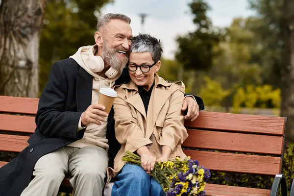 A mature couple sits closely together on a park bench, enjoying each others company. — Stock Photo