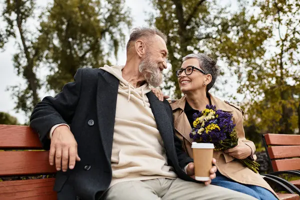 Ein reifes Paar genießt zärtliche Momente gemeinsam im Park und tauscht Lächeln und Lachen aus. — Stockfoto