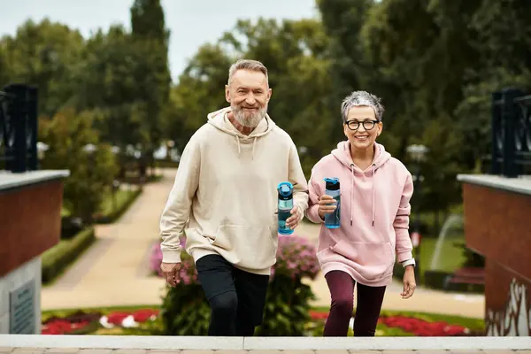 A mature couple walks in a vibrant park, sharing smiles and love while enjoying nature. — стокове фото