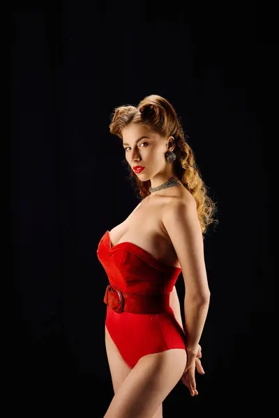 Elegante giovane donna che indossa un abito rosso sorprendente mette in mostra la grazia e il fascino in una posa accattivante — Foto stock