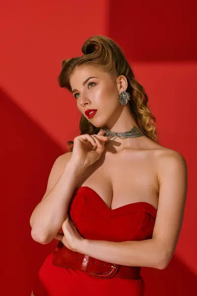 Uma mulher elegante em um vestido vermelho posa graciosamente contra cores vibrantes. — Fotografia de Stock