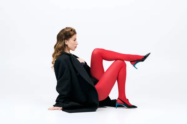 Chic young woman poses confidently in stylish outfit, flaunting vibrant red tights and heels. — Stock Photo