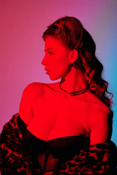 An appealing young woman poses gracefully in captivating red and blue lighting, exuding style. — Stock Photo