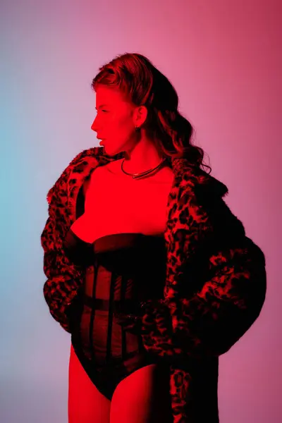 Uma jovem mulher chique confiantemente posa em luz de néon impressionante, mostrando seu olhar elegante. — Fotografia de Stock