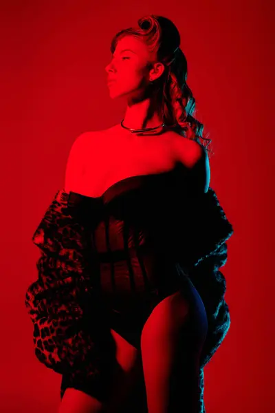 In a vivid red backdrop, a confident young woman showcases her chic style. — Stock Photo