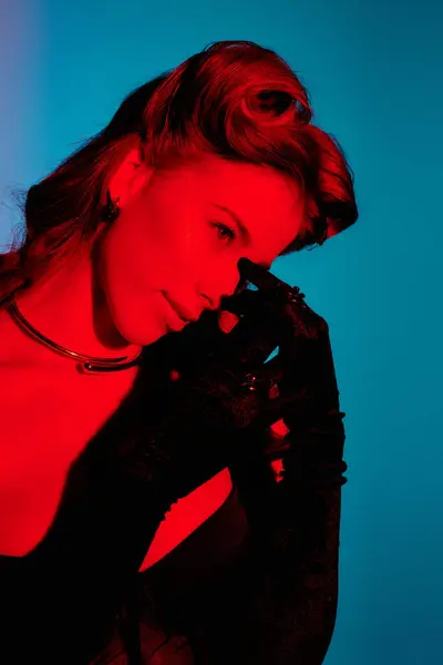 Una mujer joven con estilo posa encantadoramente en la iluminación vibrante, mostrando su encanto. - foto de stock