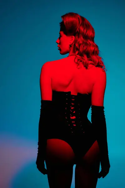 Jovem elegante mostra sua roupa elegante enquanto posando elegantemente sob iluminação dramática. — Fotografia de Stock