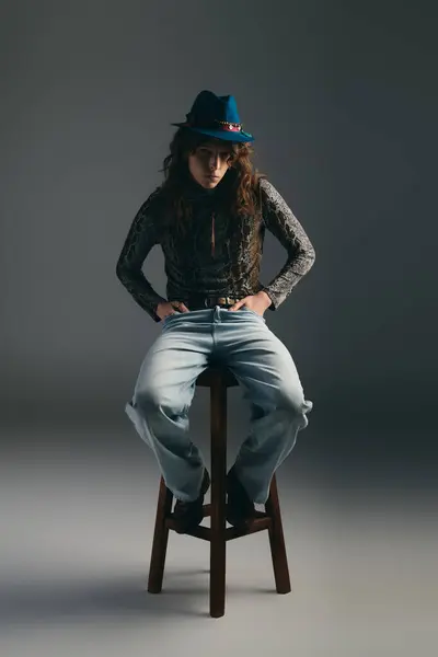 A young, stylish man poses on a wooden stool, radiating personality. — Stock Photo