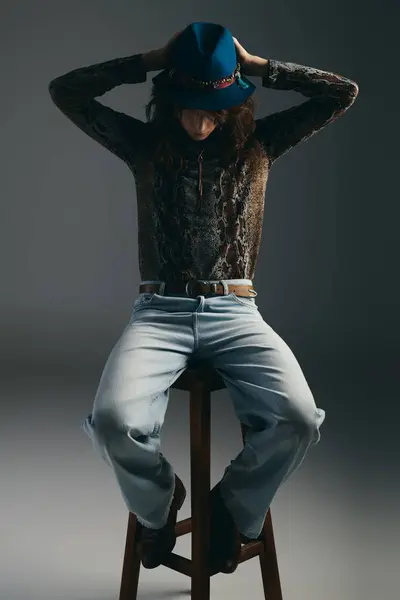 A dapper young man reflects in a stylish outfit while seated on a wooden stool, exuding confidence. — Stock Photo