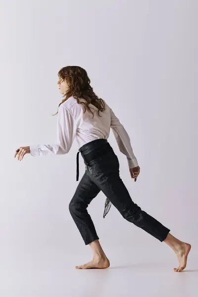 A handsome man moves gracefully in a chic studio, showcasing modern fashion and effortless style. — Stock Photo