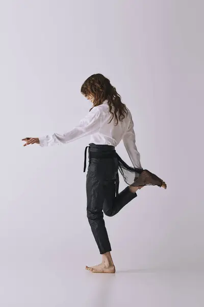 A handsome young man showcases his elegance while dancing barefoot in a modern studio. — Stock Photo