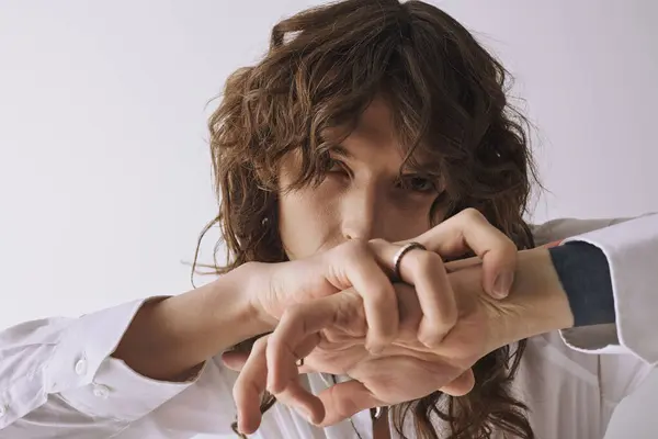A handsome young man with wavy hair expresses creativity through an artistic gesture. — Stock Photo