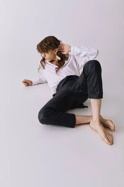A fashionable young man lies on the floor, exuding charm with a unique pose and attire. — Stock Photo