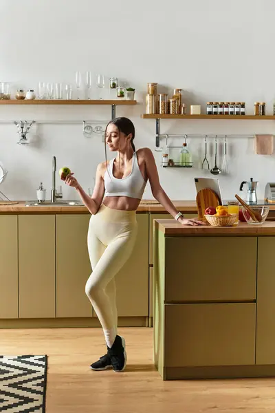A beautiful young woman dances joyfully in her modern kitchen, embracing fitness and wellness. — Stock Photo