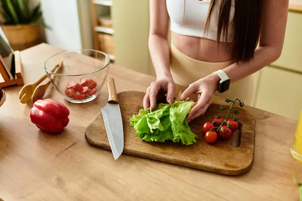 Tiro cortado de uma jovem mulher em sportswear habilmente prepara uma salada colorida usando legumes frescos. — Fotografia de Stock