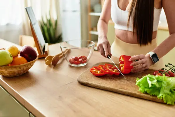 Cropped shot of young woman in sportswear prepares a colorful salad in a sunny kitchen. — Stock Photo
