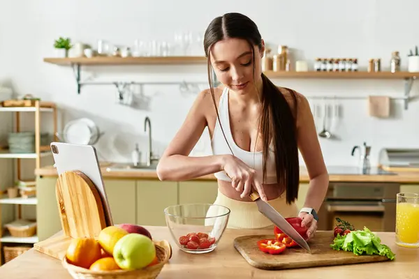 A young fit woman in sportswear skillfully prepares a fresh salad in her cozy kitchen. — Stock Photo