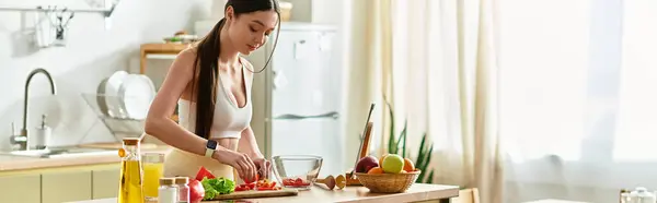 In a bright kitchen, a fit woman in sportswear prepares a fresh salad with vibrant ingredients, banner — Stock Photo