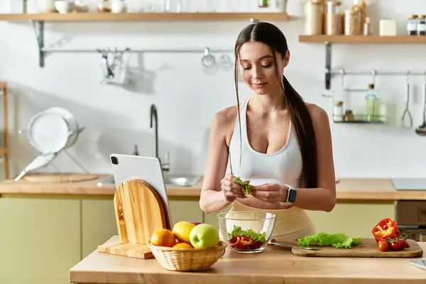 A fit young woman prepares fresh vegetables for a colorful salad in a stylish kitchen. — Stock Photo