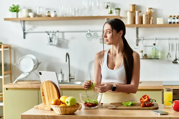 A fit woman prepares a colorful salad, showcasing her love for healthy cooking in the kitchen. — Stock Photo