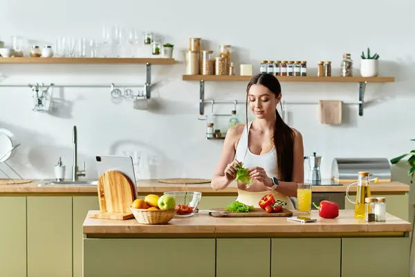 A beautiful young woman in sportswear skillfully prepares a vibrant salad in her kitchen. — Stock Photo