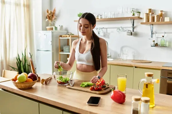 A fit woman makes a healthy salad in her stylish kitchen with fresh ingredients. — Stock Photo