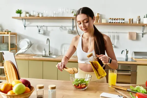 Apto jovem mulher habilmente mistura ingredientes de salada fresca em sua cozinha moderna. — Fotografia de Stock