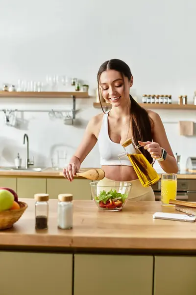 A young and fit woman prepares a vibrant salad in a stylish kitchen, embracing healthy cooking. — Stock Photo