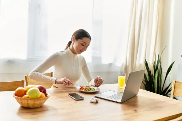 A young woman relishes a healthy breakfast of salad and juice at home, embracing wellness. — Stock Photo
