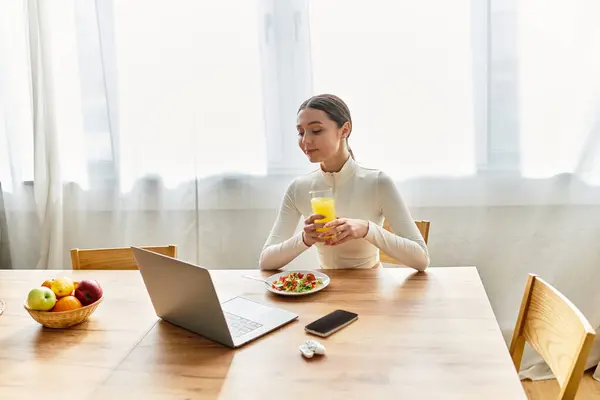 A young woman savors a nutritious breakfast while sitting at her kitchen table, feeling refreshed. — Stock Photo