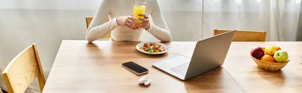 A young woman savors a healthy breakfast while seated at her kitchen table, banner — Stock Photo