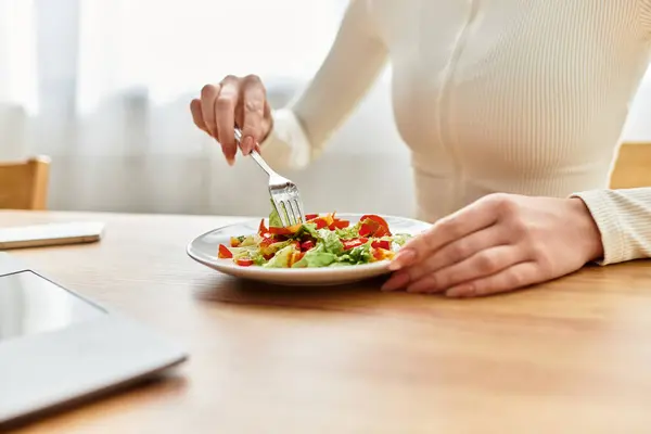 Eine junge Frau genießt einen köstlichen Salat zum Frühstück, umgeben von einer warmen Küche. — Stockfoto