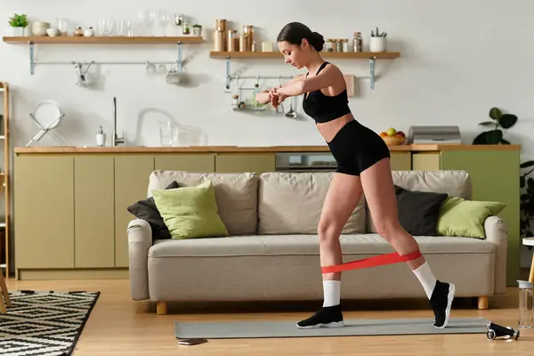 In a chic apartment, a young woman in black sportswear works out, focusing on fitness. — Stock Photo