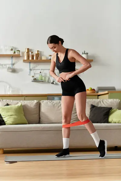 Una hermosa joven está haciendo ejercicio en su elegante apartamento, estirándose con determinación. - foto de stock