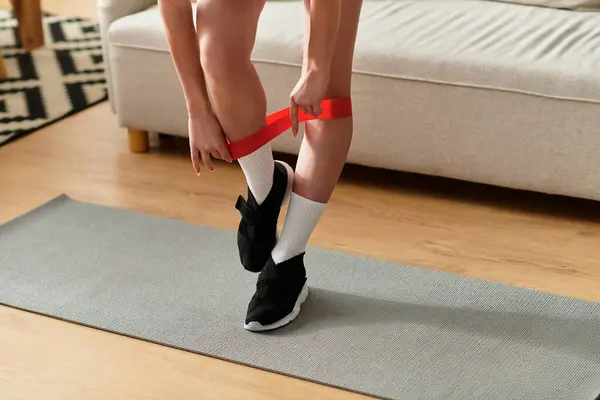 Recortado de ejercicios de mujer joven en su apartamento moderno, centrándose en sus objetivos de fitness. - foto de stock