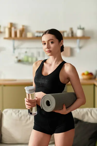 Mulher bonita no sportswear preto se prepara para seu treino em um apartamento moderno. — Fotografia de Stock